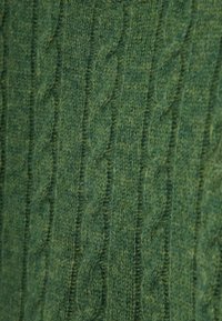Grüner gestrickter Stoff mit einem Kabelmuster, das erhöhte Texturen aufweist, weicher Haptik und einem einheitlichen Grünton.