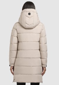 Heledanud bež puffer-jakk horisontaalse õmbluse, polsterdatud disaini, eemaldatava kapuutsiga ning elastsete mansettidega. Seljal on brändi logo.