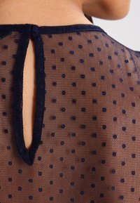 Tessuto trasparente blu navy con pois, dotato di un'apertura a golfare sul retro, caratterizzato da una superficie testurizzata e da un design leggero e morbido.