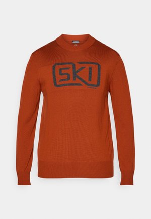 Sudadera naranja con cuello redondo, mangas largas y un logo negro de "SKI" en la parte frontal. Textura de punto con puños y dobladillo acanalados.