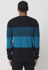 Garšs piedurkņu džemperis ar horizontālām svītrām melnā un divās zilu toņos. Adījuma tekstūra ar ribotiem aproces un apakšmalu.