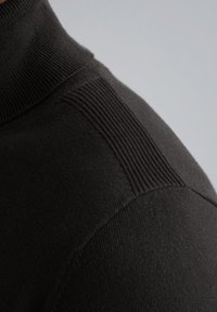 Tessuto di un maglione nero con collo alto, caratterizzato da dettagli a coste sulle spalle. Texture liscia, design aderente.