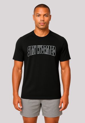 Schwarzes T-Shirt mit kurzen Ärmeln, auf dem in Weiß "STAY HYDRATED" gedruckt ist, kombiniert mit grauen Shorts aus leichtem Stoff.