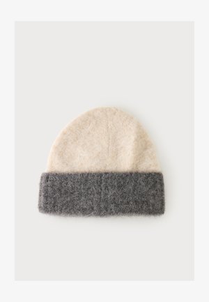 Bonnet en laine doux avec un dessus beige et une large bande de revers pliée gris foncé sur un fond uni.