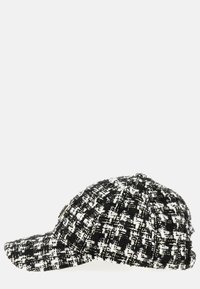 Sort-hvid tweed baseballcap med struktureret skygge, mønstret tekstur og et lille accentlogo på siden.