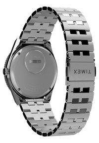 Montre en acier inoxydable Timex avec un boîtier rectangulaire, un bracelet segmenté et des accents noirs. Comprend des marques imprimées au dos.