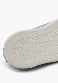 Sole boty z texturované bílé gumy s embosovaným písmem. Na viditelném světle modrém textilním okraji je mírný barevný přechod.