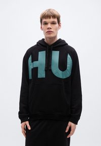 Μαύρο φούτερ με κουκούλα, με μεγάλο τιρκουάζ γράμμα "HU" στο μπροστινό μέρος, διαθέτει κουκούλα με κορδόνι και μπροστινή τσέπη. Κατασκευασμένο από μαλακό και ανθεκτικό ύφασμα.