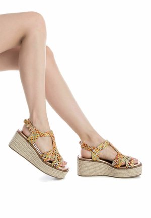 I sandali con zeppa presentano un design a strisce intrecciate arancioni e gialle, una soletta in pelle liscia color beige e una suola piattaforma in juta testurizzata.