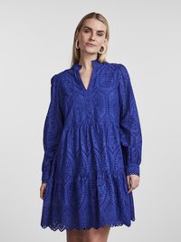 Blå, mönstrad klänning med lång ärm, volangkrage, lager av skörtar och utstansade detaljer längs fållen och bodyn.