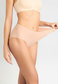 Beżowa, bezszwowa bielizna o wysokim kroju. Miękki, elastyczny materiał o gładkiej fakturze i niewidocznych szwach.