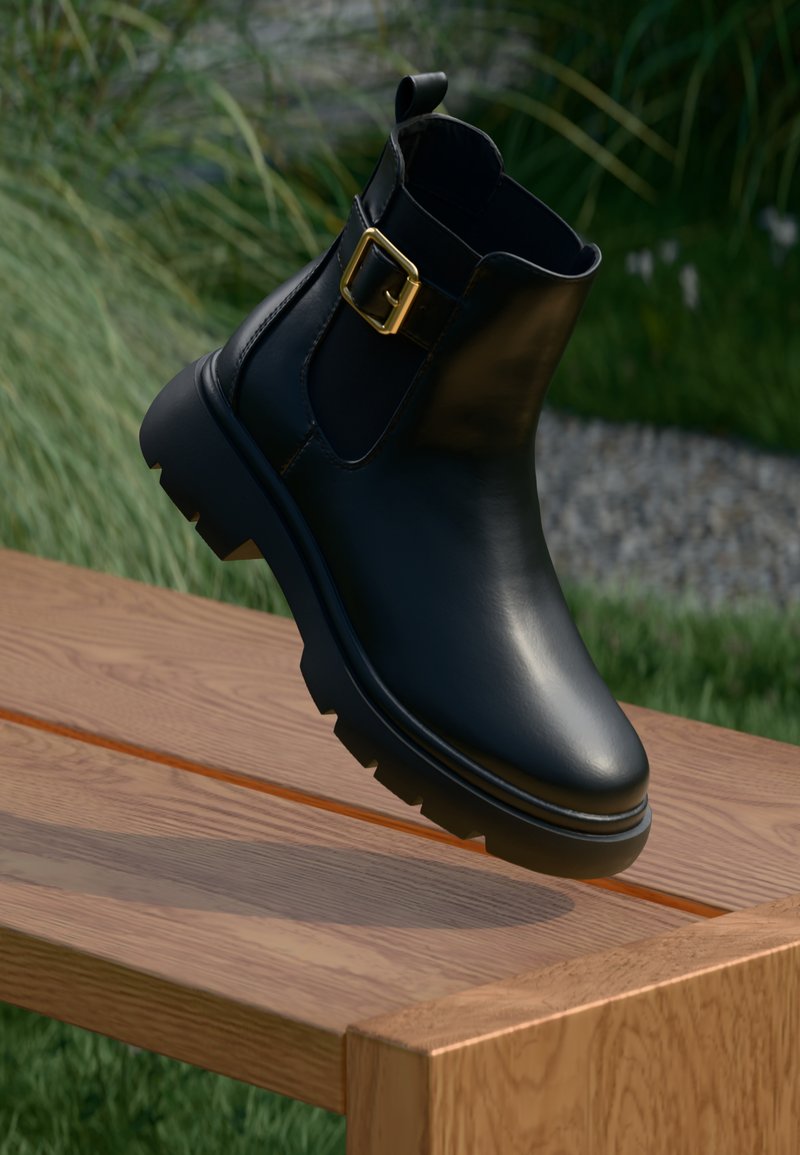 Black leather ankle boot with a shiny finish, gold buckle detail, and rugged sole. Elevated position against a wooden surface.