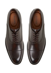Scarpe eleganti in pelle marrone con una finitura liscia, punta affilata e cuciture decorative. Presentano un design con lacci e lacci in tono.