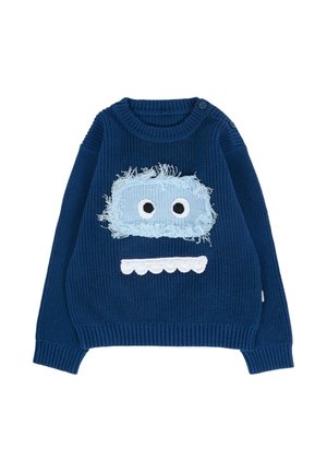 Pull en tricot bleu avec texture côtelée, comportant un patch en fourrure bleu clair sur le devant avec de grands yeux blancs et un détail de bouche blanche en bordure.