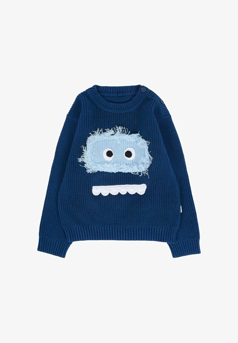 Pull en tricot bleu avec texture côtelée, comportant un patch en fourrure bleu clair sur le devant avec de grands yeux blancs et un détail de bouche blanche en bordure.