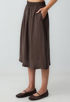 Jupe marron mi-longue avec une taille élastique froncée et des poches latérales ; faite d'un tissu léger avec une texture lisse.