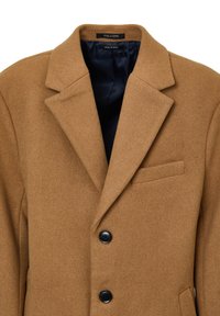 Cappotto in misto lana marrone con revers, bottoni neri e tasca sul petto. L'interno è foderato con una tinta unita blu scuro.