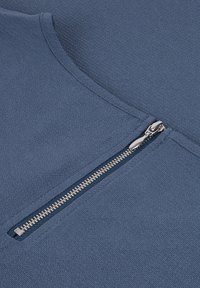 Tessuto blu testurizzato con un dettaglio di cerniera argento sul lato. Il collo è arrotondato e il tessuto sembra resistente e morbido.