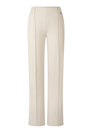 Pantalons larges beige avec une texture lisse, dotés de plis avant et d'un design minimaliste. Détail de logo discret près de la taille.