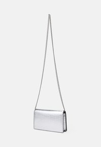 Sudraba metāla kluču soma ar gludu tekstūru, taisnstūra formu un ķēdes jostu. Īpašības ietver minimālistisku dizainu un redzamu aizdari trūkumu.