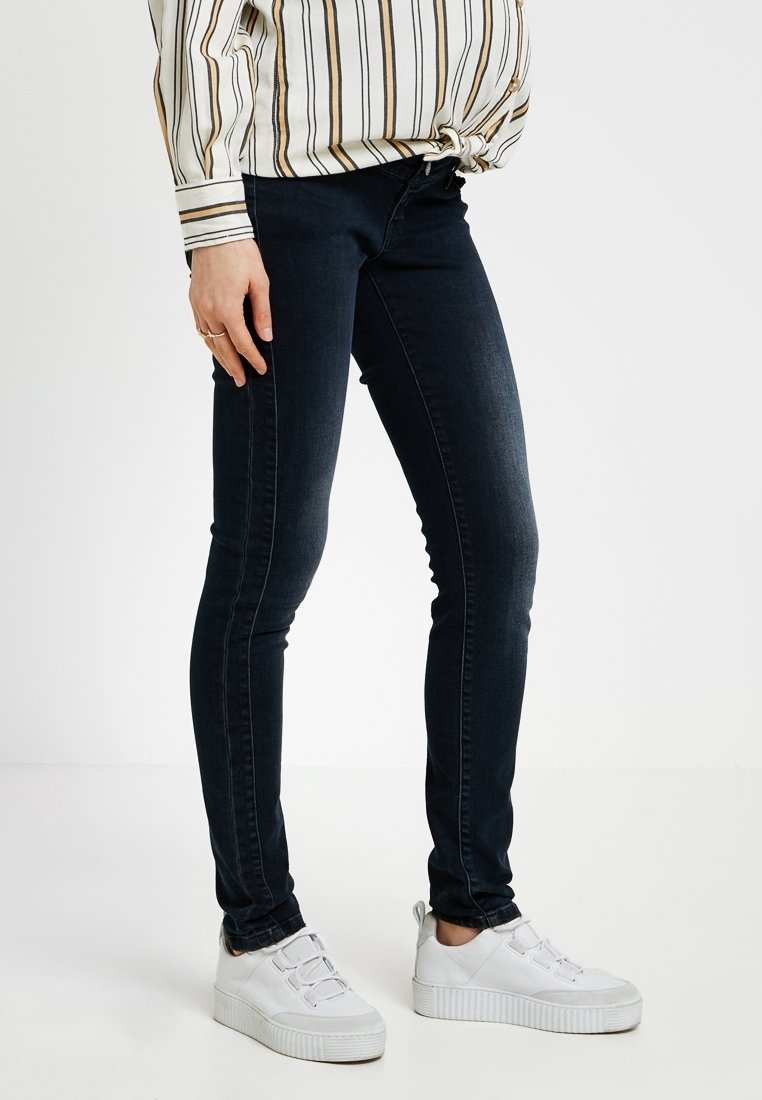 Mörka slim fit-jeans med en slät yta, med medelhög midja och subtila sömnadsdetaljer. Bärs med vita sneakers.