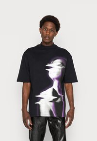 Black oversized t-shirt with a graphic in white and purple depicting a distorted figure, featuring a high neckline and short sleeves.