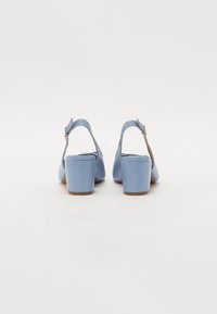 Lys blå høye sandaler med lukket tå, brede blokkhæler og justerbar ankelrem. Glatt tekstur med minimal detaljering.