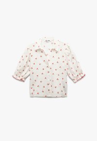 Camicia bianca con maniche puffate corte, decorata con un motivo di ciliegie in rosso e verde. Include una chiusura frontale con bottoni e bordi delle maniche arricciati.