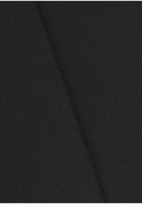 Tessuto nero visto da un'angolazione, che mette in evidenza una superficie liscia. Il materiale presenta cuciture sottili lungo il bordo per una maggiore resistenza.