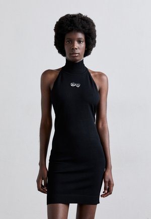 Black knit sleeveless dress with a high neck. Features a fitted silhouette and ribbed hem. Notable silver emblem design on the chest.