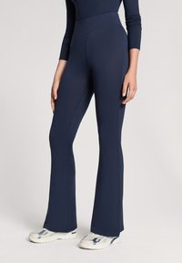Pantaloni yoga a gamba svasata blu navy con una vita alta, realizzati in un tessuto elasticizzato. Texture liscia senza motivi o dettagli visibili.