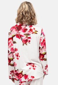 Witte top met lange mouwen en bloemenpatroon, voorzien van opvallende roze en rode bloemen. Soepele stof met een ontspannen pasvorm en ronde hals.