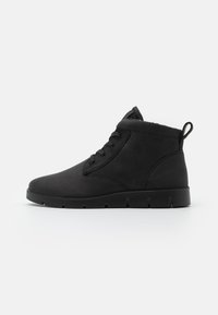 Botas negras hasta el tobillo con un upper sintético suave, diseño de cordones, punta redonda y suela de goma texturizada con una pestaña de agarre.
