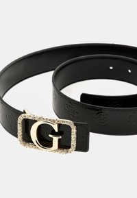 Schwarzer Ledergürtel mit einer strukturierten Oberfläche, ausgestattet mit einer goldfarbenen Schnalle, die mit Strasssteinen verziert ist, sowie einem auffälligen "G"-Logo.