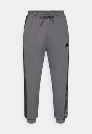 Γκρι αθλητικό παντελόνι από απαλό ύφασμα, με μαύρο πλαϊνό πάνελ και ρυθμιζόμενη μέση με κορδόνι. Λογότυπο Adidas μπροστά.