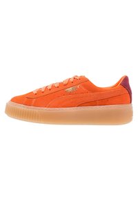 Baskets en suède orange avec un bout arrondi, semelle en caoutchouc texturée et accent de talon bordeaux contrasté. Présente un logo doré sur le côté.