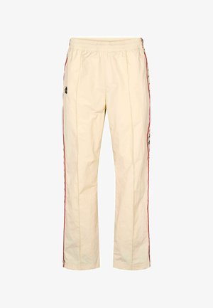 Svijetlo bež sportske hlače s elastičnim remenom s vezicom u struku, crvenim bočnim prugama i izvezenim logotipima na oba nogavica. Glatka, lagana tkanina.