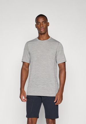 Lichtgrijze, t-shirt met korte mouwen en een subtiel gestreept patroon en een ronde hals. Gecombineerd met donkerblauwe shorts, met zijzakken.