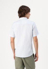 Light blue short-sleeve shirt in a soft, textured fabric, featuring a collared neckline, and a curved hemline. Back view shows minimal design details.