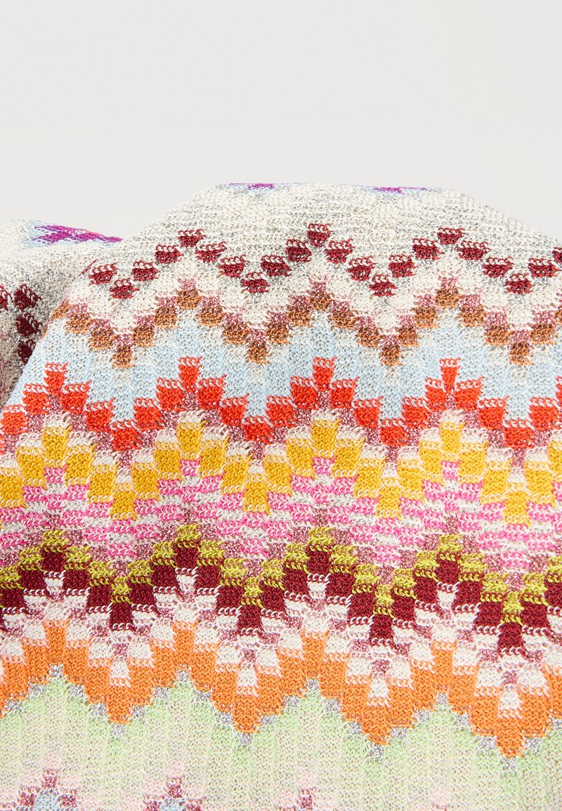 Kleurrijke gebreide stof met geometrische patronen in tinten wit, rood, oranje, geel, roze, groen en blauw, gevouwen met zichtbare textuur.