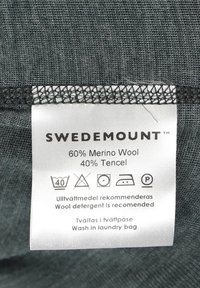 Label for fabric blend, white with black text, indicating 60% merino wool and 40% Tencel, with washing instructions and care symbols.