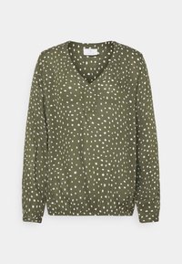 Blouse à manches longues couleur vert olive, avec un col en V, un ourlet froncé et un motif à pois blancs. Confectionnée dans un tissu léger au toucher lisse.