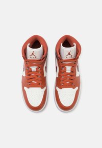 Paire de baskets montantes en blanc et orange brûlé avec lacets, embout perforé et logo Jumpman Air sur la languette, vues de dessus.