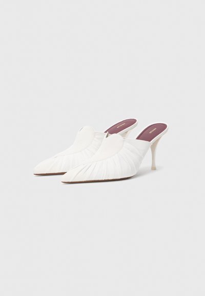 Λευκές μυτερές μύτες mules με υφή και πλισέ επάνω μέρος. Διαθέτουν λεπτό, διαφανές τακούνι και μαλακό εσωτερικό πέλμα σε μπορντό χρώμα.