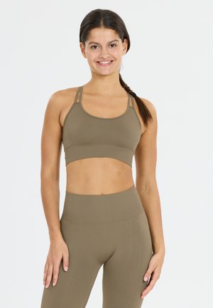 Olijfgroene sportbeha met een aansluitend design, verstelbare bandjes en een gladde, rekbare stof. Gecombineerd met hoge, bijpassende leggings.