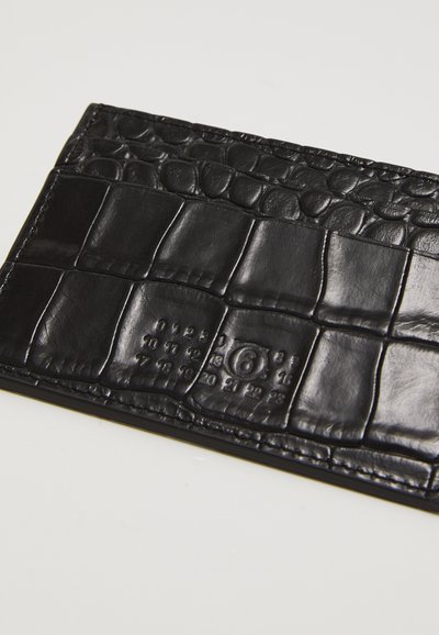 Carteira de couro preto com um padrão de crocodilo texturizado, forma plana e detalhes em relevo. Superfície lisa com um acabamento brilhante.