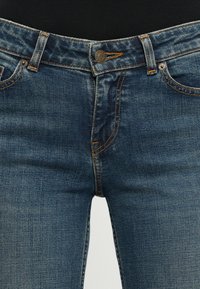 Denim jeans med standard passform, mørkeblå farge, synlig søm og klassisk fem-lomme design med metallknapplukking.