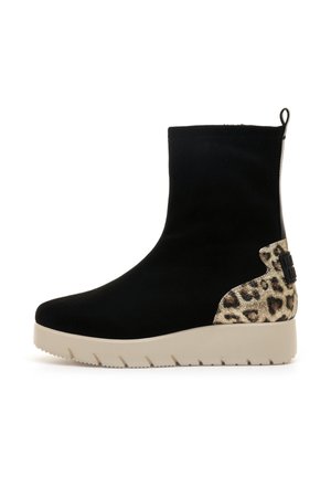 Botín negro de ante hasta el tobillo con un acento de estampado de leopardo texturizado en el talón y una suela de plataforma beige. Presenta una lengüeta para facilitar su uso.