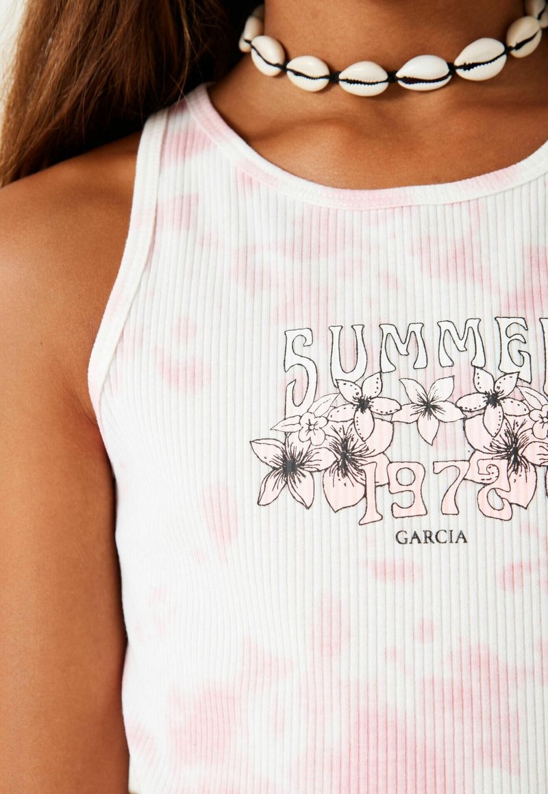 Top bianco a coste con accenti rosa tie-dye e una stampa grafica con fiori. Completo con un collier a conchiglia bianco.