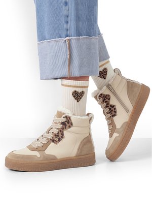 Beige hoge sneakers met luipaardprintaccenten en wollen voering, gedragen met witte sokken met luipaardhartmotieven en opgerolde lichtblauwe spijkerbroeken.
